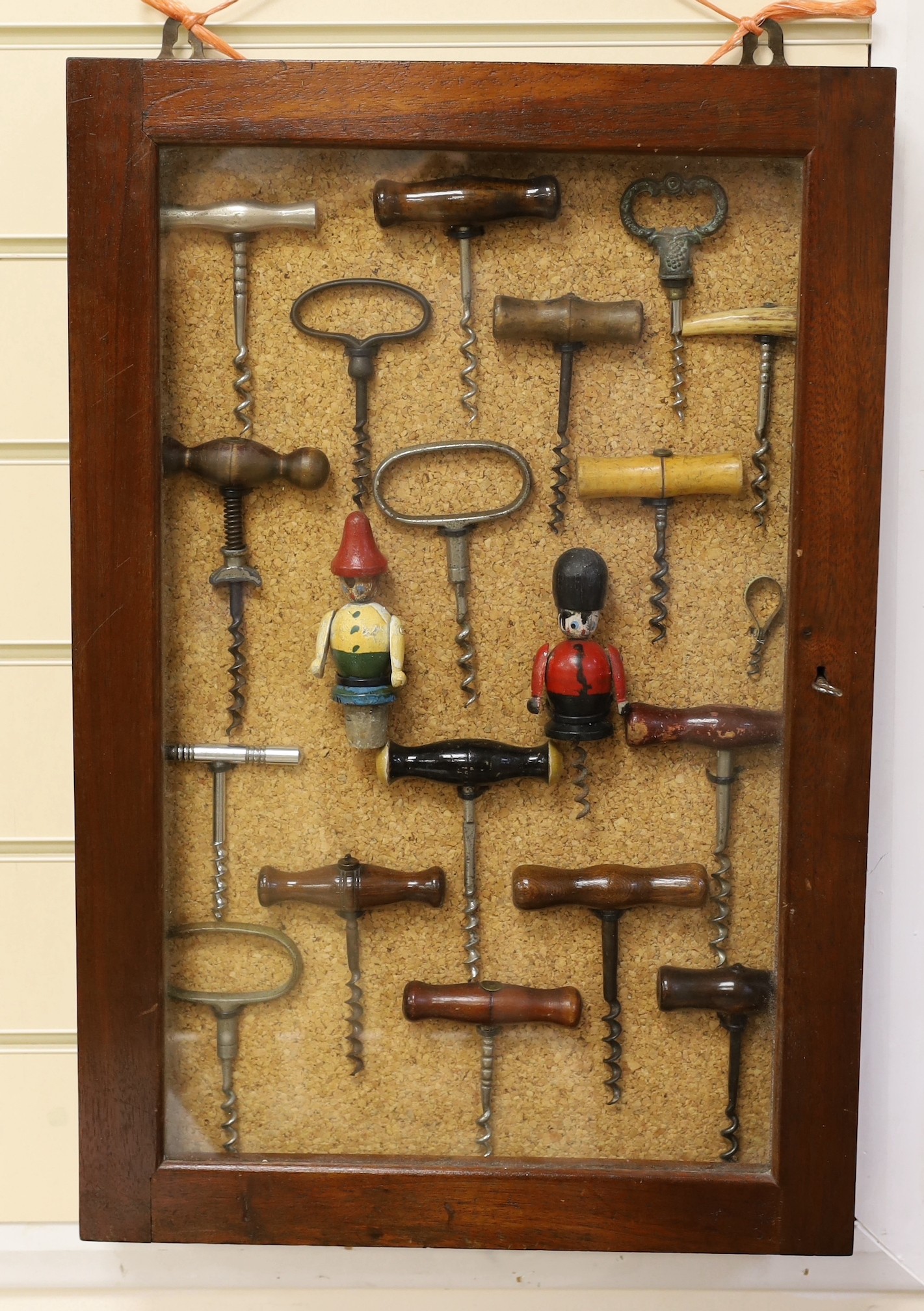 A collection of vintage corkscrews, some novelty, in glazed mahogany vase with key